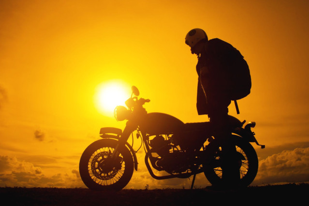 Motorradfahrer und Motorrad vor Sonnenuntergang