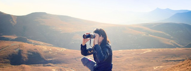 Eine Frau auf Reisen schaut durch ein Fernglas